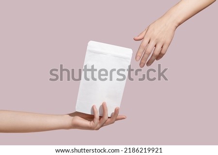 Female hand holds white cardboard packaging for tea, coffee, snack on pink background. Branding and packaging mockup. High quality photo