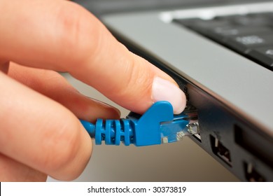 Female Hand Inserting A Blue Networking Ethernet Cable Into A Laptop	