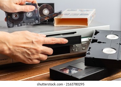 Female Hand Inserts VHS Videocassette Put Into Video Recorder To Watch Video. Female Hand Holds Old Magnetic Audio Tape Cassette For Music. Retro Vintage Technology Concept