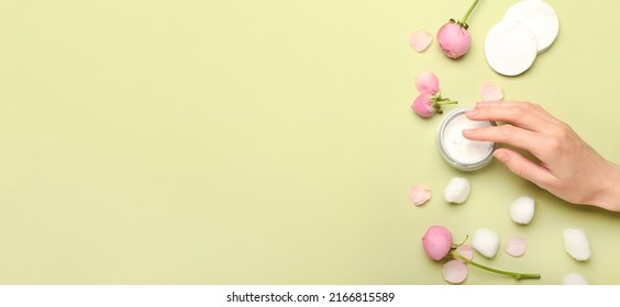 Female Hand With Jar Of Cosmetic Cream, Cotton Balls, Pads And Rose Flowers On Green Background With Space For Text