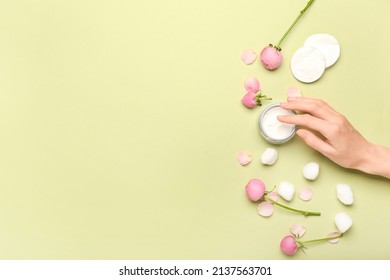 Female Hand With Jar Of Cosmetic Product, Cotton Balls, Pads And Rose Flowers On Green Background