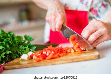 Female hand with knife cuts bell pepper in kitchen. Cooking vegetables - Powered by Shutterstock