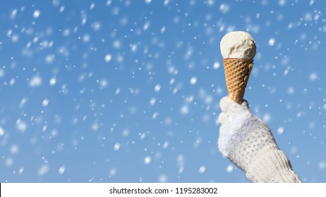 Female Hand In Knitted Gloves With Ice Cream In A Waffle Horn On The Winter Snowfall Background. Concept 