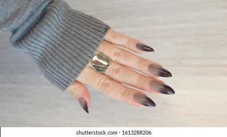 Female hand and long nails   beige brown manicure holds bottle nail polish