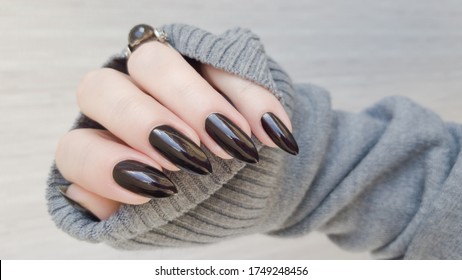 Female hand with long nails and black manicure holds a bottle of nail polish
