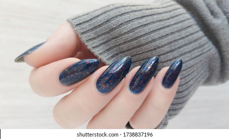 Female hand and long nails   blue manicure and bottles nail polish