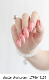 Female Hand With Long Nails And A Bottle Of Bright Pink Neon Nail Polish