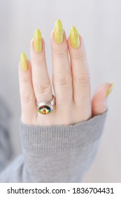 Female Hand With Long Nails And A Bottle Of Bright Yellow Green Nail Polish