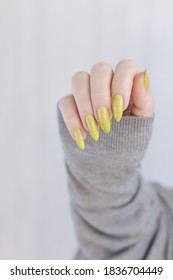 Female Hand With Long Nails And A Bottle Of Bright Yellow Green Nail Polish