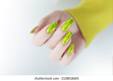 Female Hand With Long Nails And A Bottle Of Bright Yellow Green Neon Nail Polish