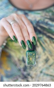 Female hand and long nails   green manicure and bottles nail polish