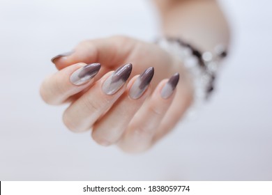 Female hand and long nails holds bottle gray  brown thermo nail polish