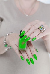 Female Hand With Long Nails And Neon Green Manicure With Bottles Of Nail Polish