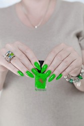 Female Hand With Long Nails And Neon Green Manicure With Bottles Of Nail Polish