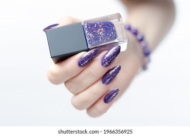 Female hand and long nails   purple lilac manicure holds bottle nail polish