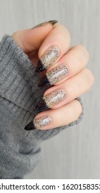 Female hand and long nails   white gray   black manicure holds bottle nail polish
