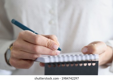 Female hand makes notes in notebook closeup