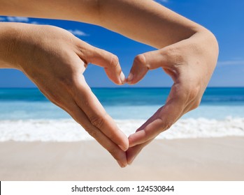 Female Hand Making A Heart Shape Against A Beautiful Blue Sky