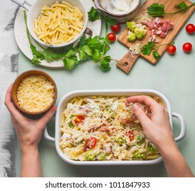 Female Hand Making Pasta Casserole With Tomato, Bacon And Cheese, Top View. American Style Hearty Macaroni Pasta In Cheesy Sauce