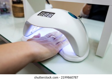 Female Hand With Manicured Nails Inside A UV Lamp In A Nail Salon