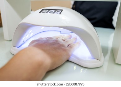 Female Hand With Manicured Nails Inside A UV Lamp In A Nail Salon