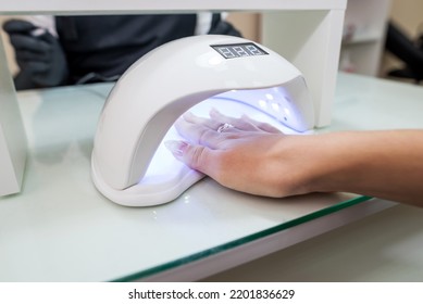 Female Hand With Manicured Nails Inside A UV Lamp In A Nail Salon