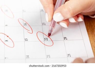 female hand marking with a red pen on a calendar circles the day, deadline concept