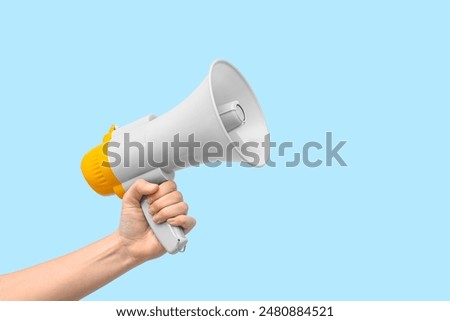 Female hand with megaphone on blue background