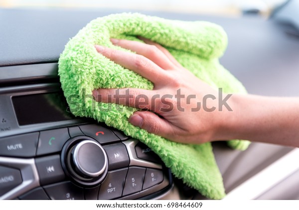 A female hand with a\
microfibre cloth cleans the panel of a modern car and the radio\
tape recorder from dust, the concept of professional washing or car\
wash
