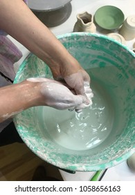 Female hand mixing paint in a bucket, clay pottery class