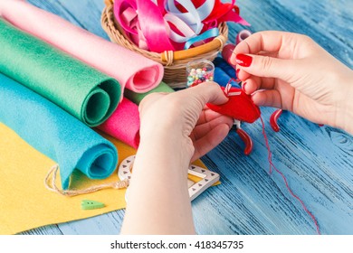Female hand with needlework objects on blue wood table