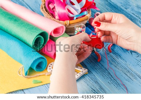 Female hand with needlework objects on blue wood table