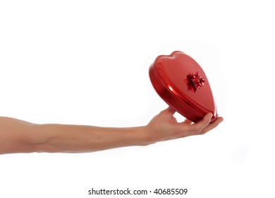 Female Hand Offering Heart Shaped Chocolate Box With Bow.  Studio, White Background.