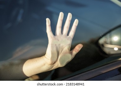 Female Hand On A Car Window Pane In The Sun. Heat Wave, Danger.