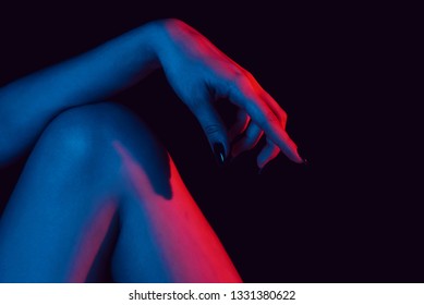 Female Hand On Knee Close Up With Red Blue Neon Light On Black Background