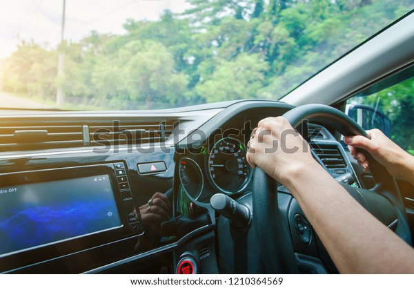 Female hand on the steering wheel driving a car on\
the park.