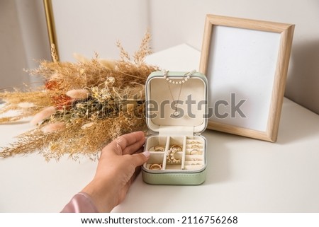 Female hand with opened jewelry box on white table