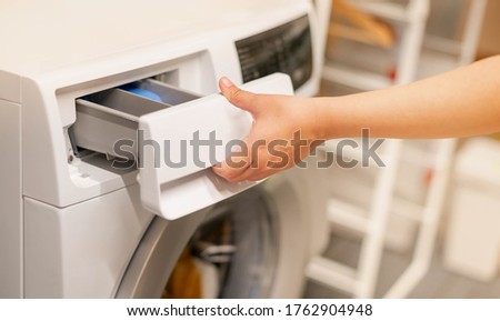 Female hand opening the washing machine and the space for detergent liquid preparing wash the clothes, for the hygience and cleaning.