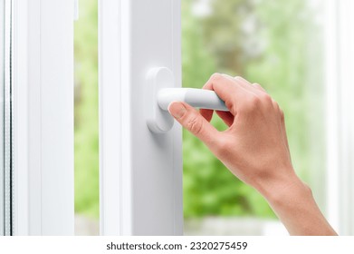 female hand opens a plastic window in a home room (PVC plastic)