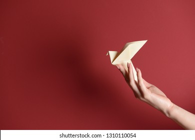 Female Hand With Origami Bird On Color Background