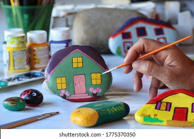 female hand painting a stone with acrylic colors, hobby to play with children
