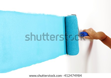 Female hand painting wall with paint roller