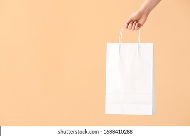 Female Hand With Paper Shopping Bag On Color Background