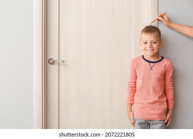 Female Hand With Pencil And Cute Little Boy Measuring Height Near Closed Door