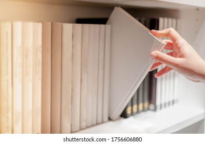 Female Hand Picking New Book On Shelf In Bookstore Shop. Personal Information Book Or Magazine For Business Or Education Research. Buying Office Supplies Concept