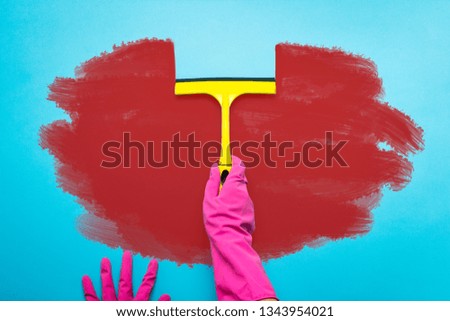 Female hand in pink gloves holding a scraper for cleaning windows and removes dirt from the surface on a blue background. The concept of cleaning the service. Flat lay, Top view