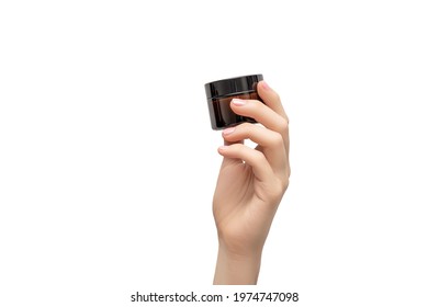 Female hand with pink nail design. Pink nail polish manicure. Woman hand hold glass jar for hand or face care cream on a white background