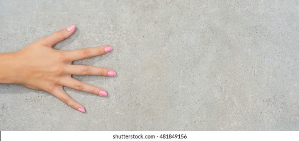 Female Hand With Pink Nails On Gray Stone Table