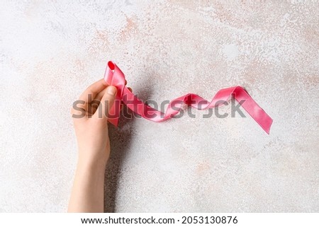 Female hand with pink ribbon on light background. Breast cancer concept