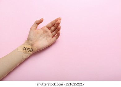 Female Hand With Plasters And Word FOOD On Color Background. Anorexia Concept